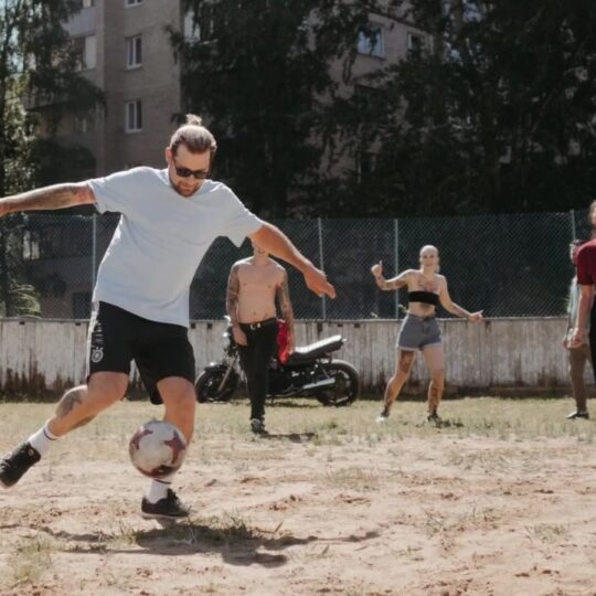 Junge Menschen spielen Fußball auf einem Platz im Freien.